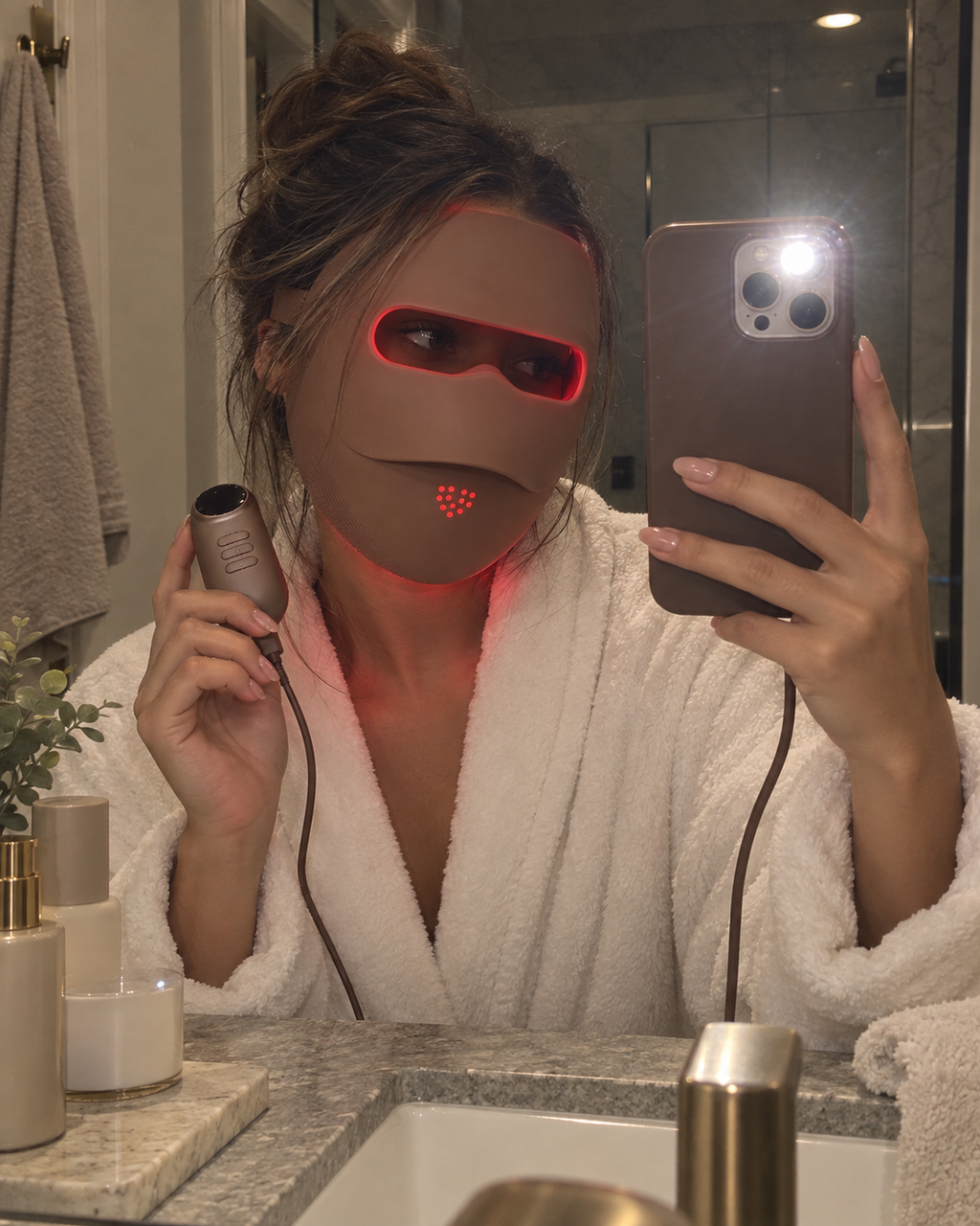 Woman wearing the glowing Auva Glow Mask in bed, warm red light on linen